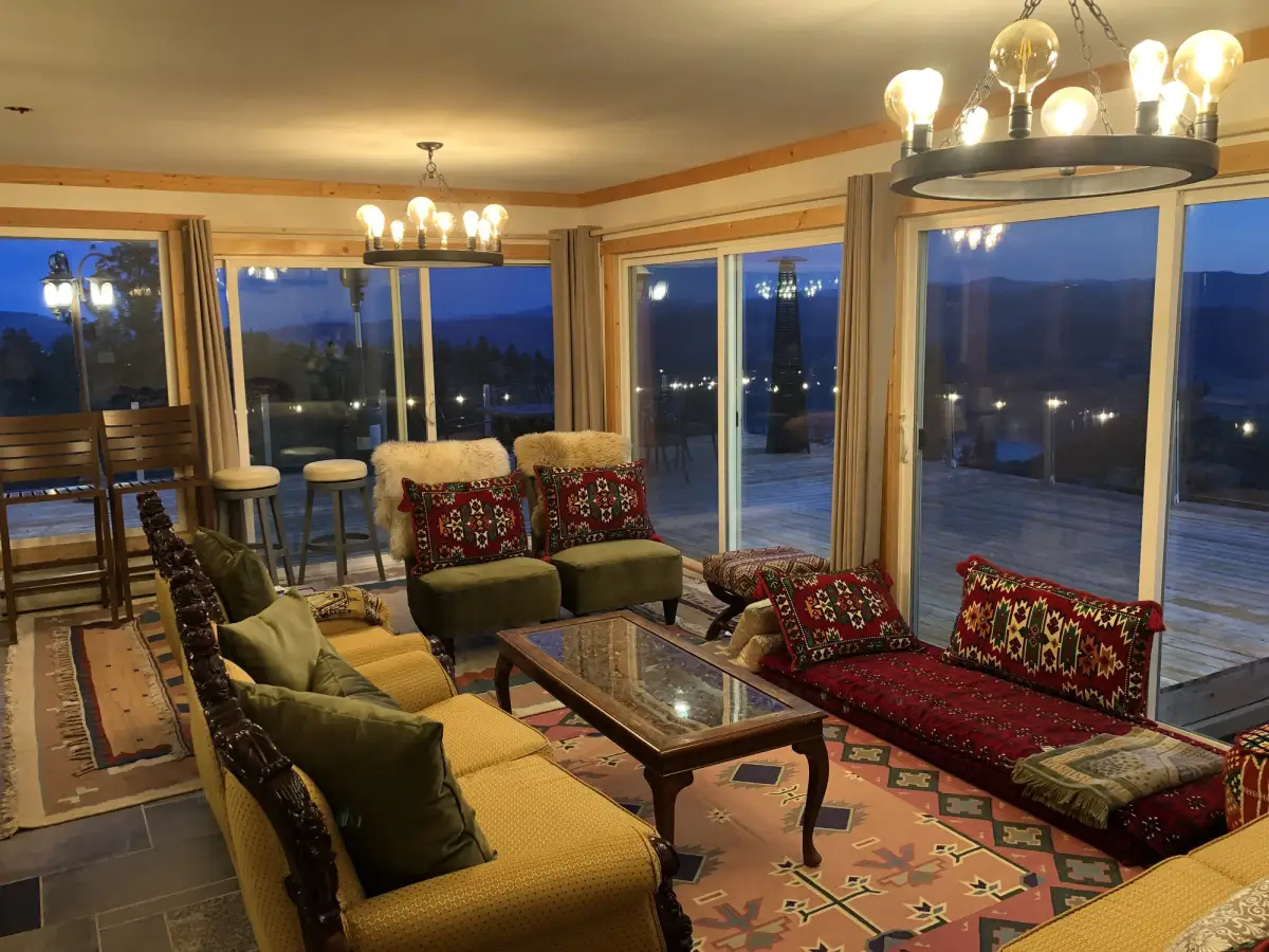 Summit Retreat living room at evening with chandeliers, eclectic colorful furniture and Osoyoos Lake views through sliding doors