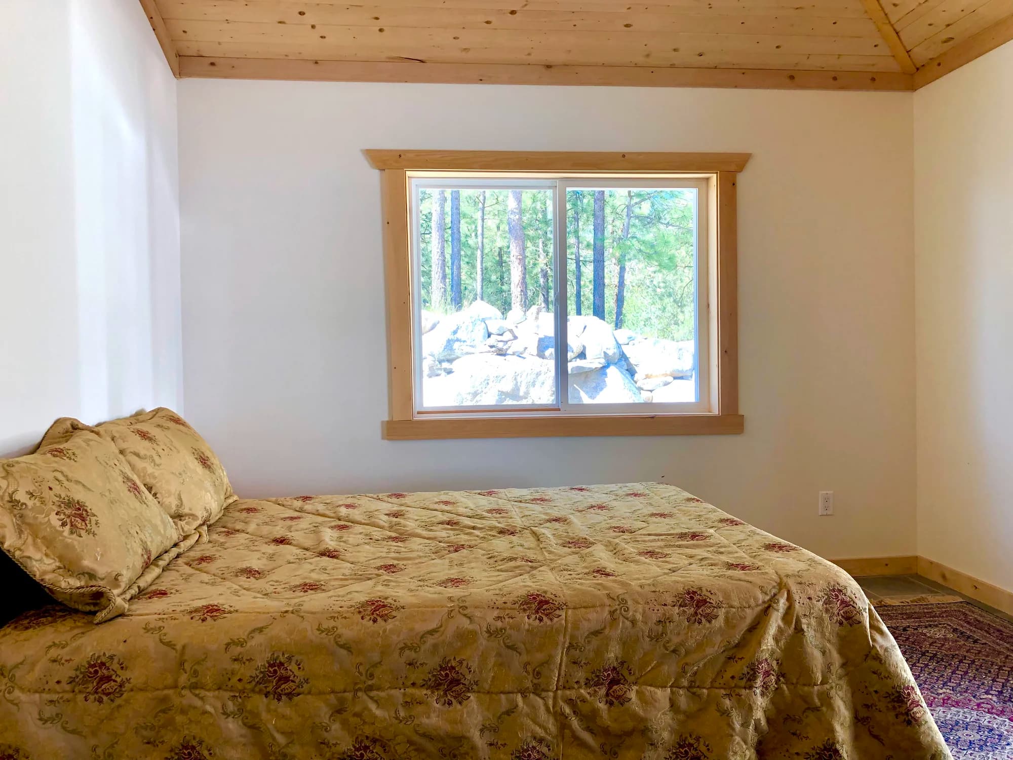 Vista Peak bedroom 4 with floral bedding, pine tree window view and knotty pine ceiling